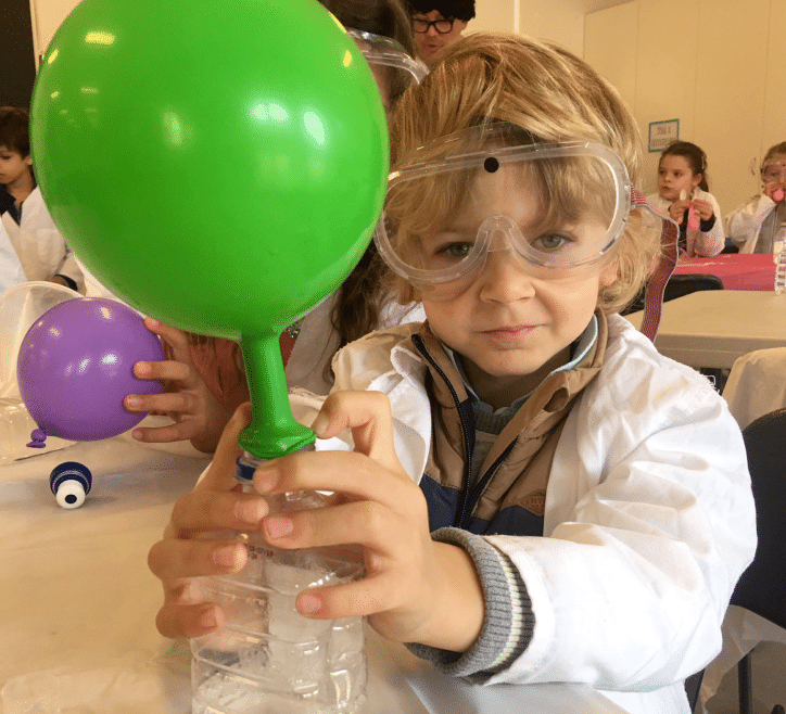 an image of a child wearing a lab coat playing with ballons